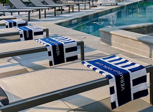 A row of sun loungers with VERNI branded towels draped over them.