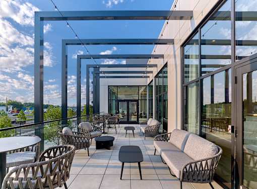 A modern outdoor seating area with wicker chairs and tables.