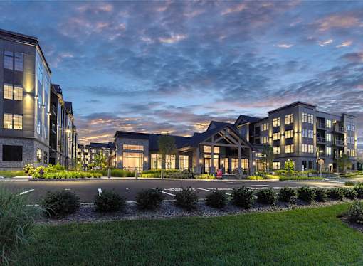 A modern building complex with a well-maintained lawn in front.
