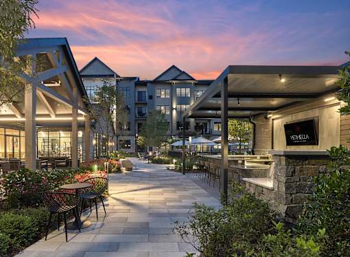 A patio with tables and chairs is surrounded by buildings.