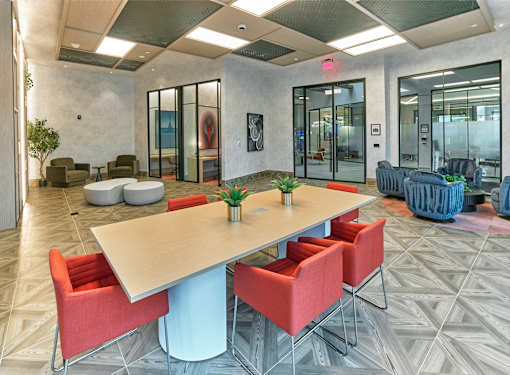 A conference room with a long table and red chairs.