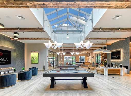 A billiards table is in the middle of a room with a skylight.