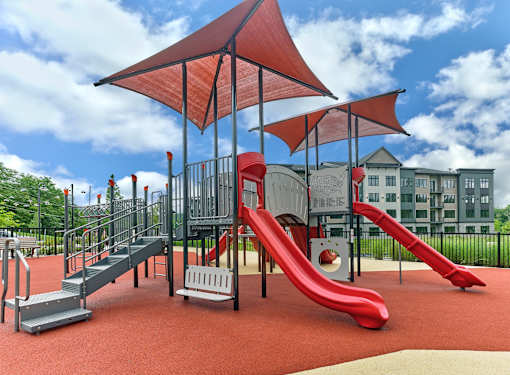 A playground with a red slide and a red canopy.