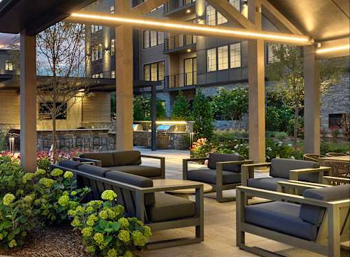 A patio with a table and chairs is lit by lights under a roof.