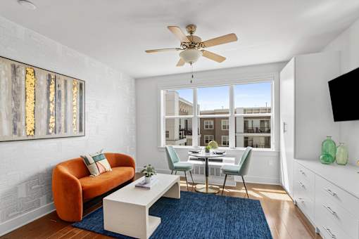 A living room with a white ceiling fan and a blue rug.