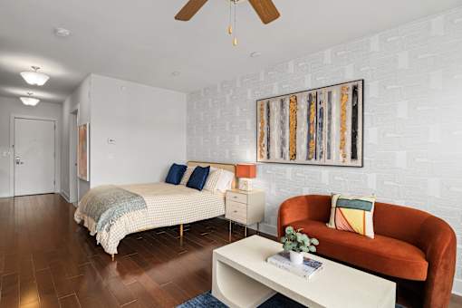 A bedroom with a bed, a couch, and a painting on the wall.