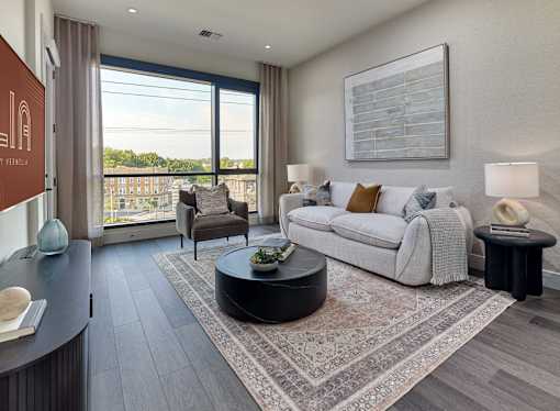 A living room with a white sofa and a large window overlooking a cityscape.