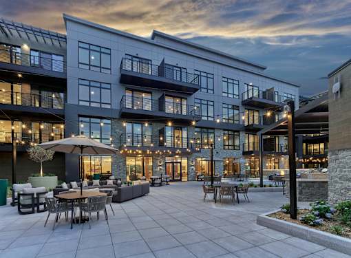 A modern apartment community with a patio and tables.
