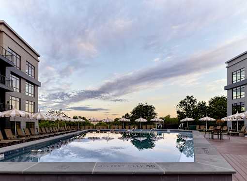 A large swimming pool surrounded by lounge chairs and umbrellas.