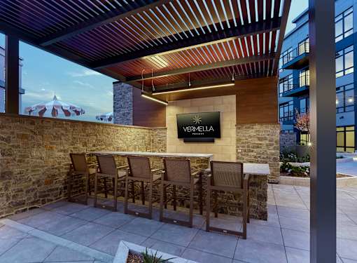 A patio area with a table and chairs in front of a stone wall and a sign that says