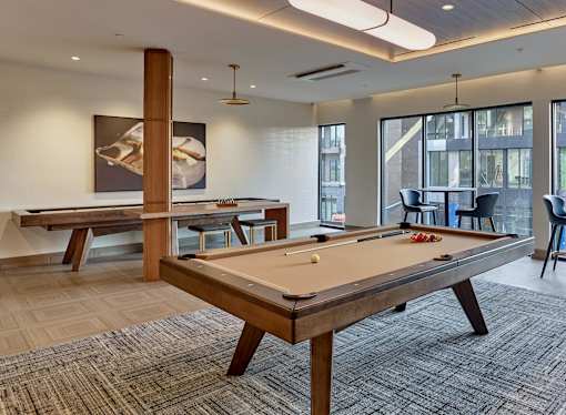 Resident clubroom with pool table, shuffleboard, bar area, fireplace feature and media area.