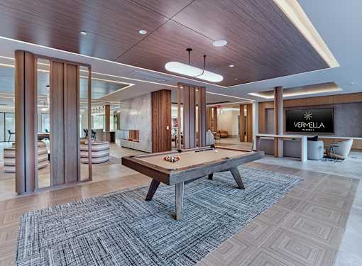 A pool table is in the middle of a room with a wooden floor and a sign that says