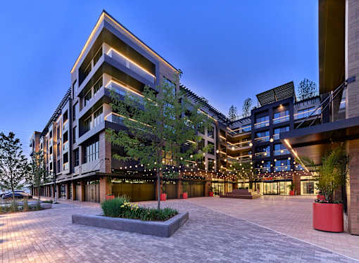 A modern building with a large courtyard and a tree in the center.