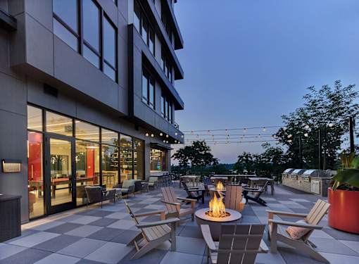 A patio with a fire pit and chairs.