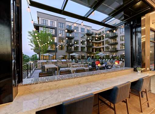 A modern outdoor dining area with a view of a multi-story apartment building.