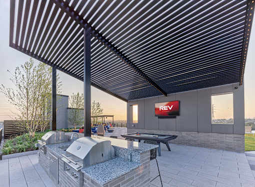 A patio with a grill and a REV sign on the wall.