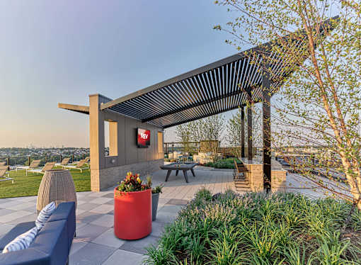 A modern outdoor seating area with a red planter and a blue sofa.