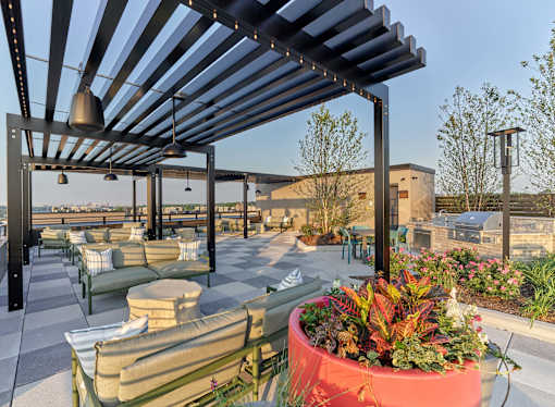 A patio with a red planter and a black metal pergola.