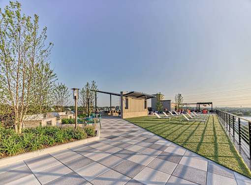 A modern outdoor seating area with a long row of chairs and a building in the background.