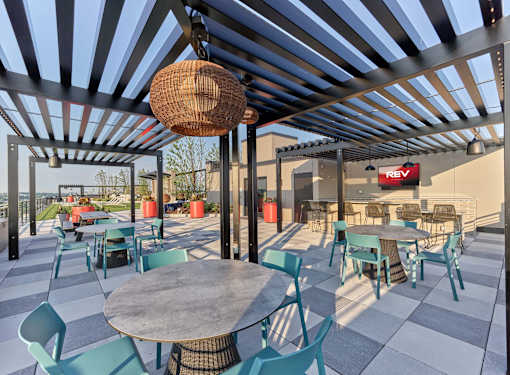 A patio with tables and chairs under a striped awning.