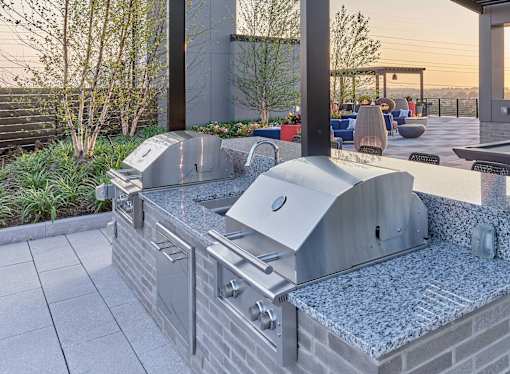 A modern outdoor kitchen with a built-in grill and seating area.
