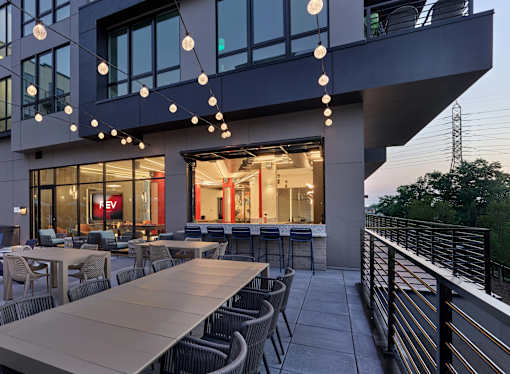A modern building with a balcony and tables set up for dining.