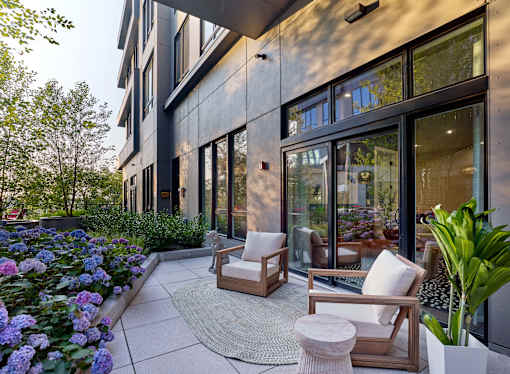 A modern patio with a white chair and a table with a potted plant.