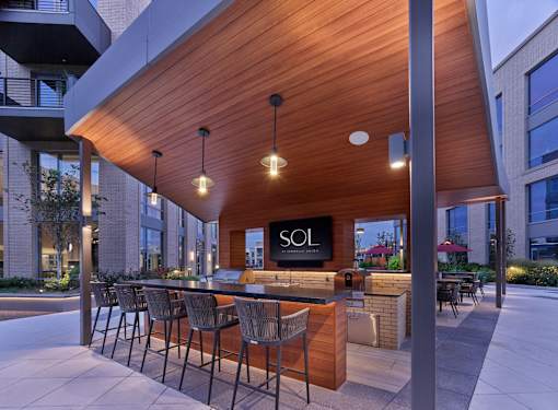 outdoor bar with grills and pizza oven, outdoor courtyard and pool table, dining seating, lounge area