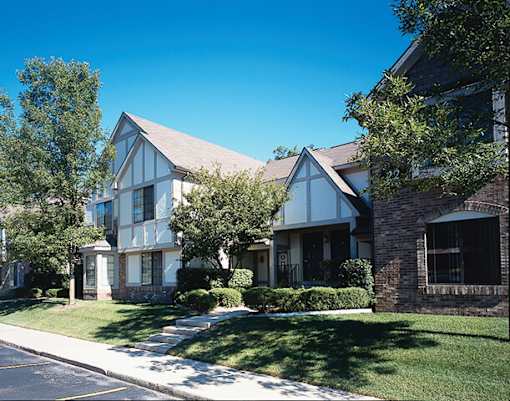 River Oaks at Rochester Hills Apartments exterior with townhouse-style buildings, landscaped lawn and walkway.