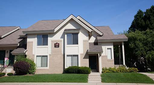 River Oaks at Rochester Hills Apartments: two-story beige townhome with manicured lawn and front walkway.