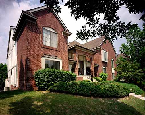 River Oaks at Rochester Hills Apartments brick townhome-style building with front steps and landscaped shrubs.