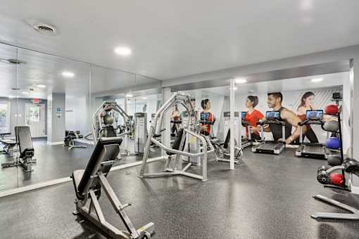 A gym with people working out and various exercise equipment.
