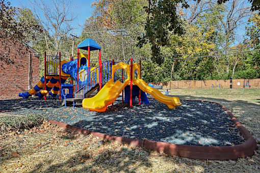 A playground with a blue and yellow slide and a red and yellow structure.