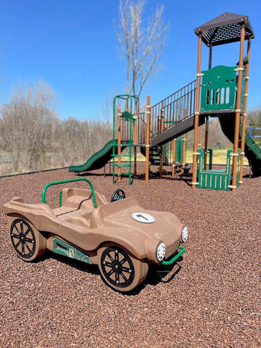 Playground at River Oaks at Rochester Hills Apartments featuring a toy car and green play structure.