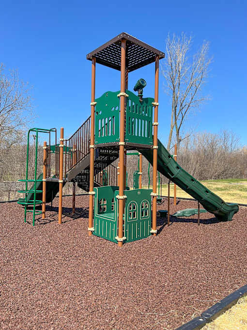 Green and brown playground tower with slide at River Oaks at Rochester Hills Apartments.