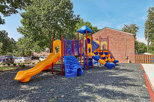 A new playground with a yellow slide and a blue and yellow climbing structure at Georgetown of St. Louis Apartments