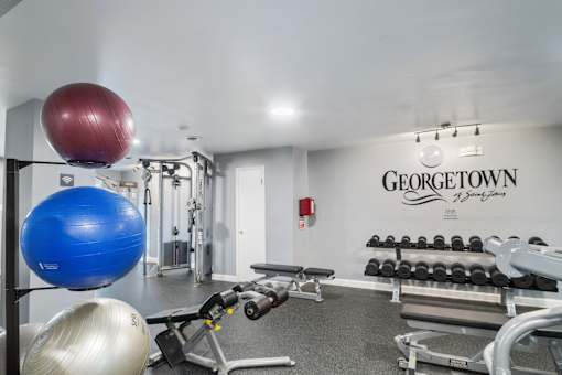 Georgetown Apartments of St. Louis fitness center with weight rack, benches, and stability balls.