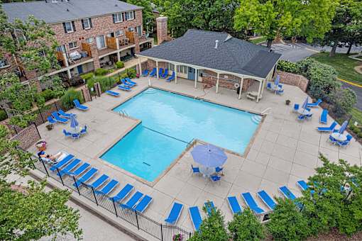 Georgetown Apartments of St. Louis pool deck with blue lounge chairs, tables, and umbrellas.