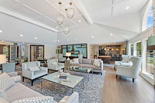 Spacious furnished community lounge with seating, pool table, and large windows at River Oaks at Rochester Hills.