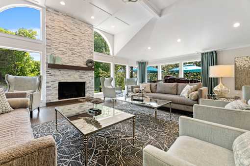 River Oaks at Rochester Hills Apartments clubhouse lounge with stone fireplace, sofas, glass coffee tables, and large arched