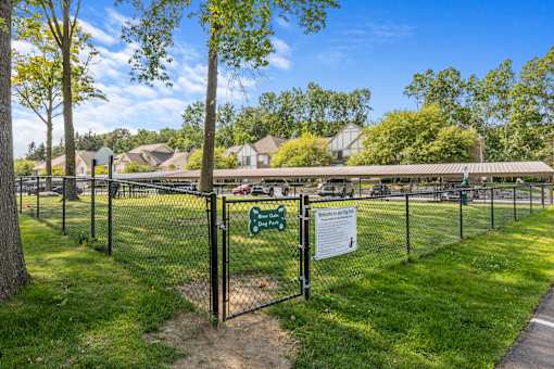 River Oaks at Rochester Hills fenced dog park with grassy play area and townhomes in the background.