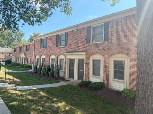 A row of red brick houses with white trim and black shutters.