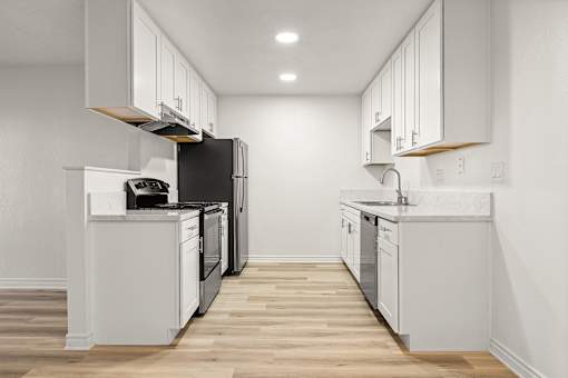 A modern kitchen with white cabinets and black appliances.