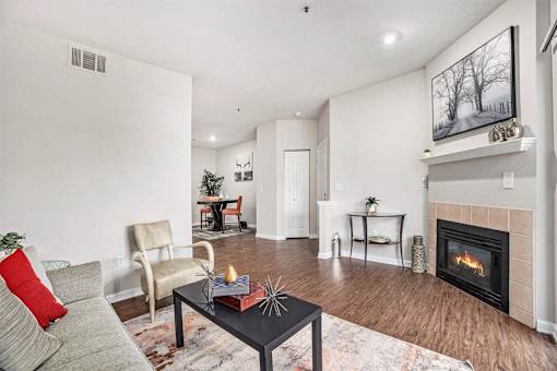 A living room with a grey couch, a black coffee table, a fireplace, and a painting on the wall.
