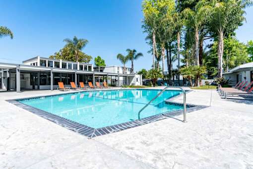 A swimming pool with a metal ladder and orange chairs.