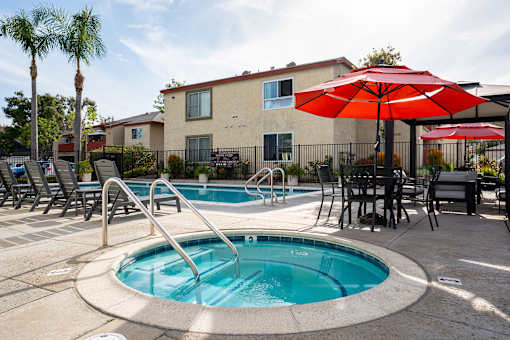 A pool with a slide and a table with chairs and umbrellas.