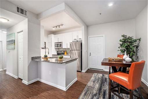 A kitchen with a bar area and a dining table with chairs.
