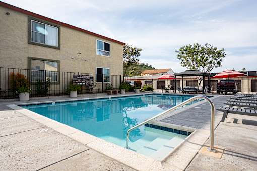 A swimming pool in front of a building with a red roof.