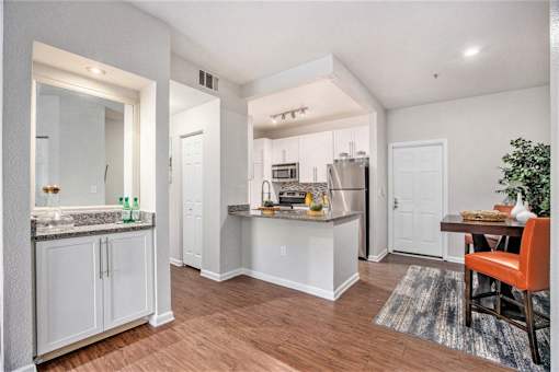 A kitchen with white cabinets and a wooden floor.