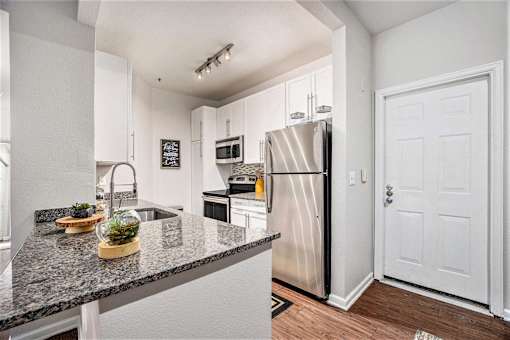 A kitchen with a granite countertop and stainless steel appliances.